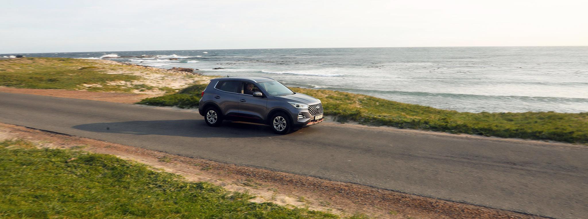 SUV driving along a coastal road with the ocean stretching to the horizon at Cape Point.