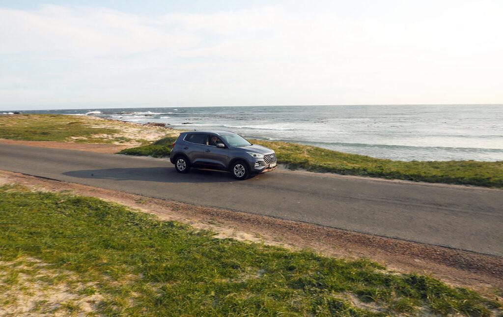 SUV driving along a coastal road with the ocean stretching to the horizon at Cape Point.