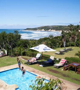 Children playing in the pool at Crawfords Beach Lodge with a sweeping view of the Wild Coast beach below.