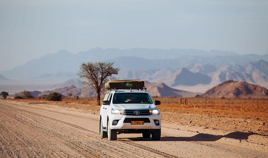 Toyota with rooftop tent on a dirt road with mountains in the background on a 4x4 self-drive tour in South Africa and Namibia.