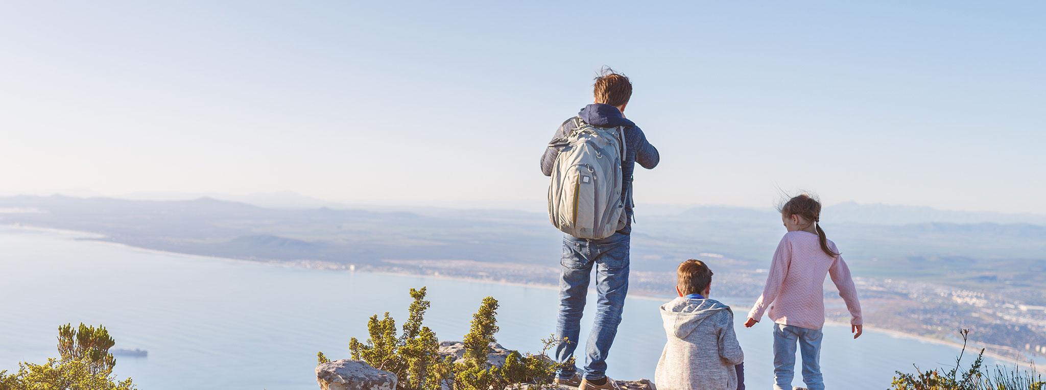 Father and his children admiring sweeping coastal views from a mountaintop