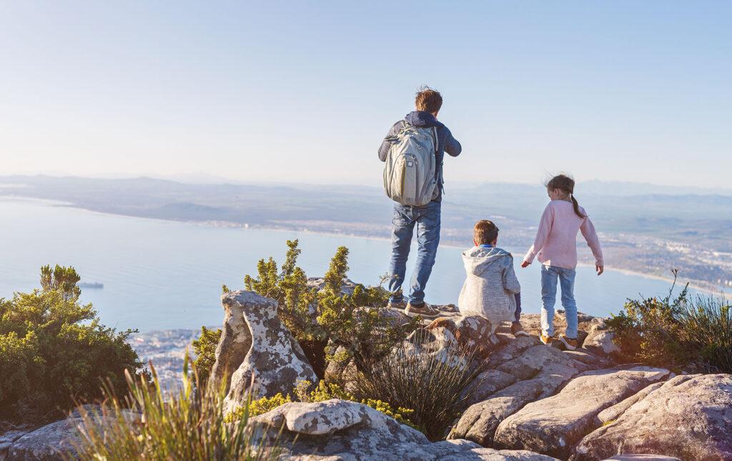 Father and his children admiring sweeping coastal views from a mountaintop