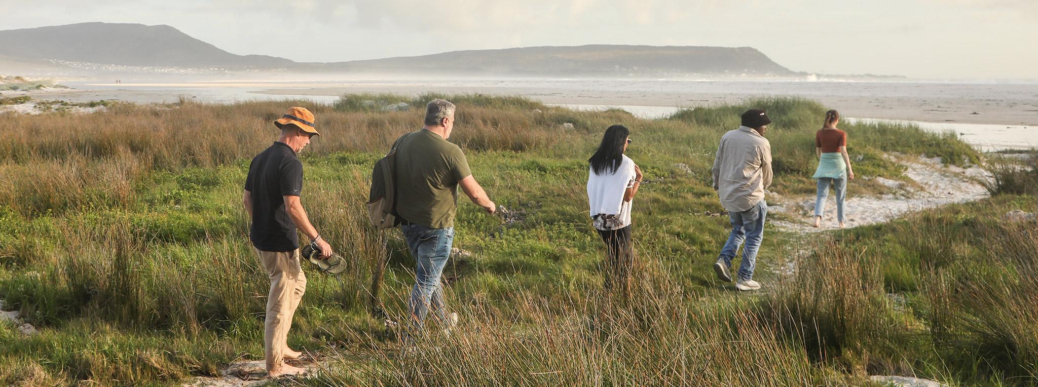 A group of guests walking to Noordhoek Long Beach during the warm season in South Africa, the best time to visit.