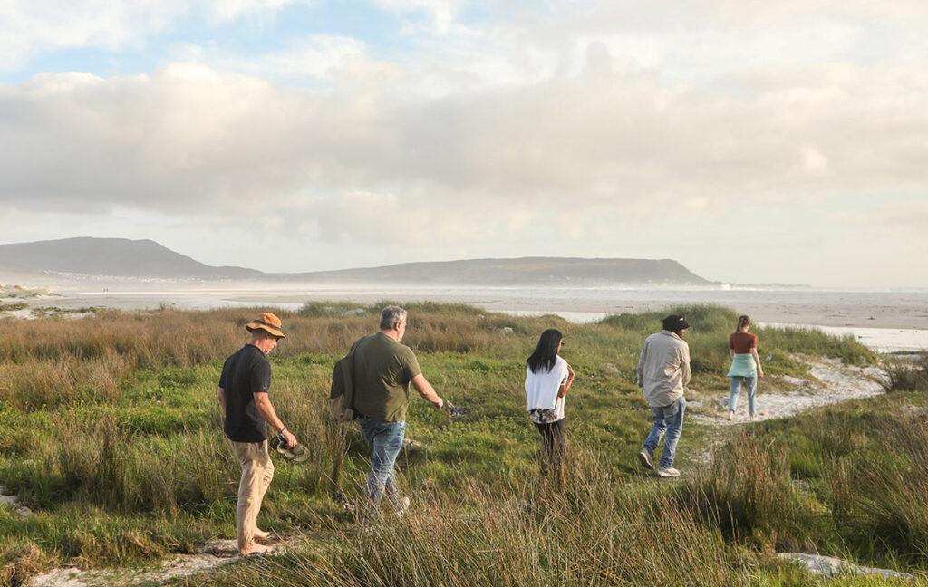 A group of guests walking to Noordhoek Long Beach during the warm season in South Africa, the best time to visit.