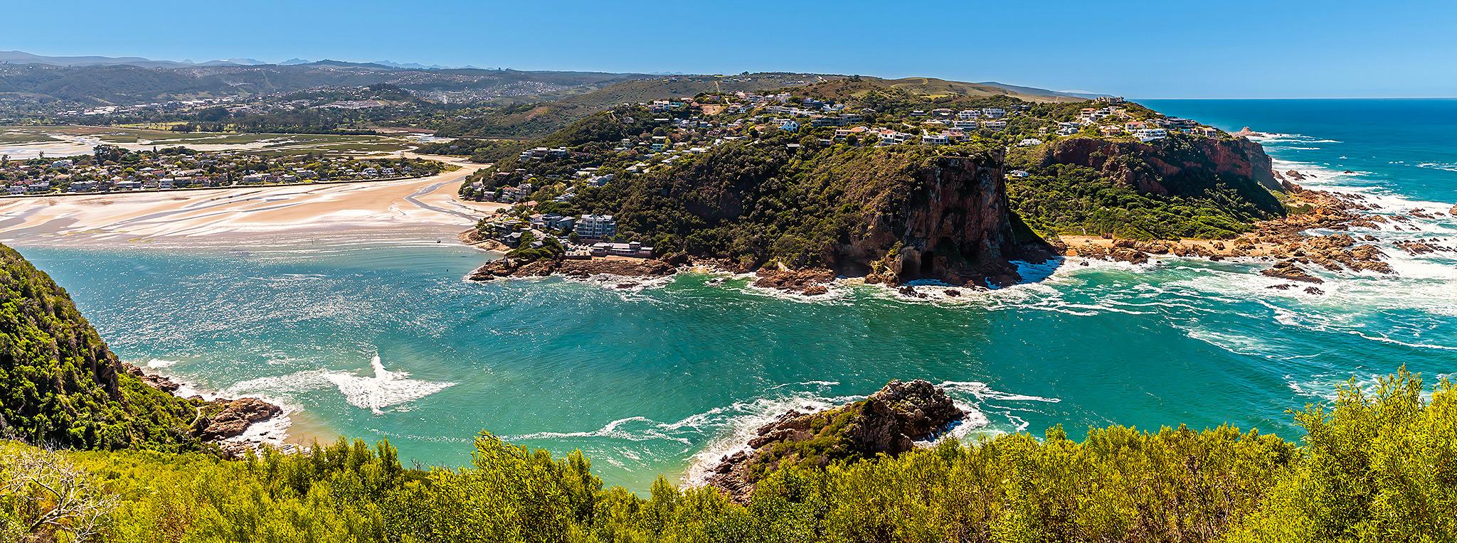 Aerial view of the Knysna Heads with turquoise lagoon entrance and clifftop homes on the Garden Route, South Africa.