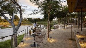 Wooden deck terrasse at Lion Sands Ivory Lodge, where you can enjoy a meal looking over a river on luxury South Africa tours.