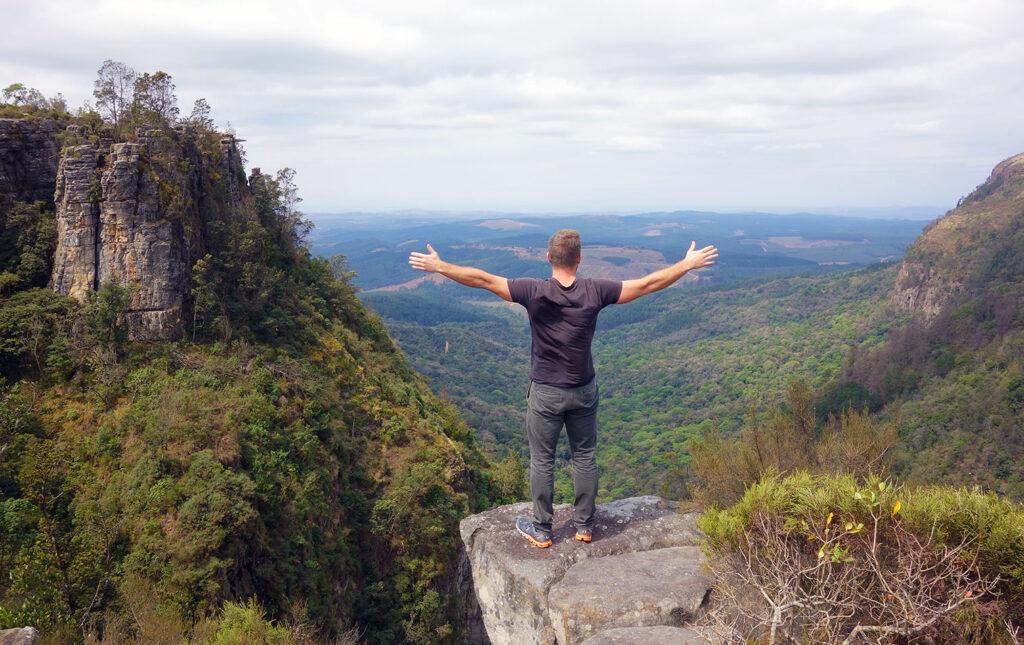 Man on a hike on the Panorama Route, stretching out his arms infront of God's Winodw.