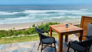 A private terrace with wooden table and chairs overlooking the beach at Mes Amis Guesthouse, Wilderness.
