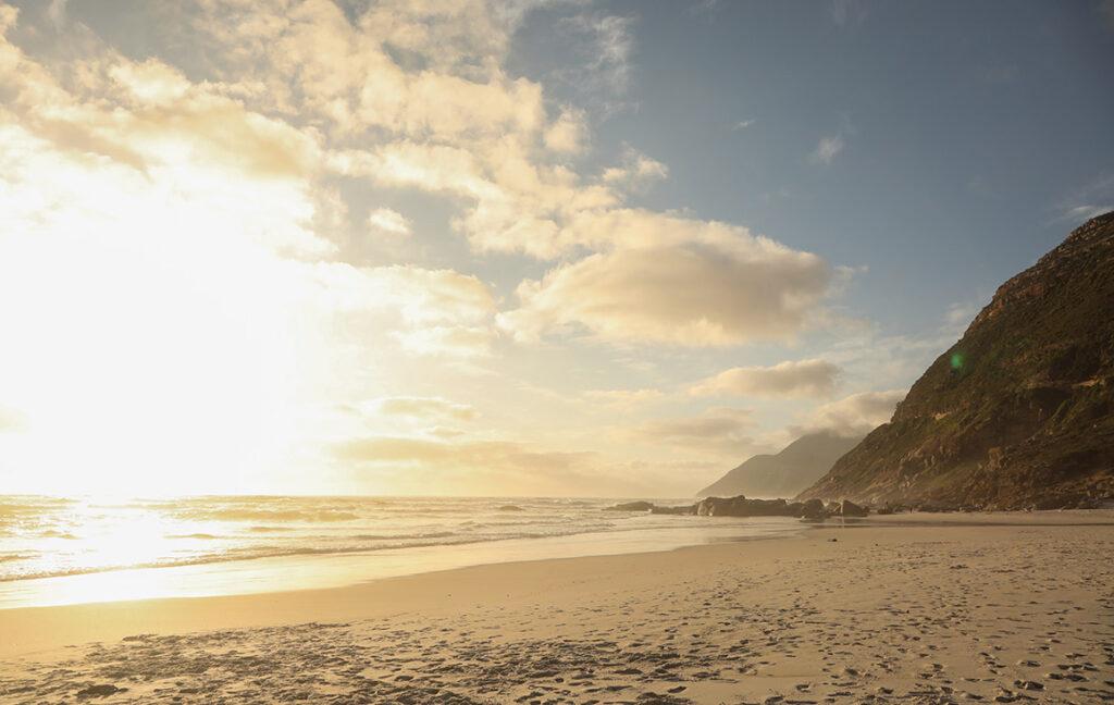The sun sets in the ocean infront of Noordhoek beach leaving a golden light on the sand.