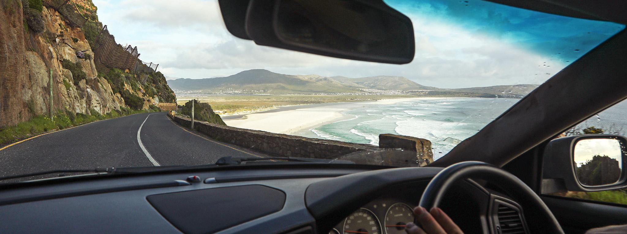 View from inside a self-drive tour vehicle driving along Chapmans Peak in South Africa.