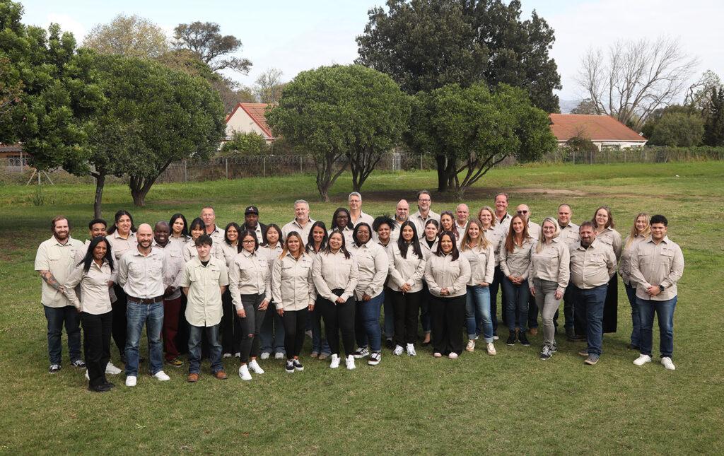 Team photo of South Affrica safari specialists in uniform outdoors.