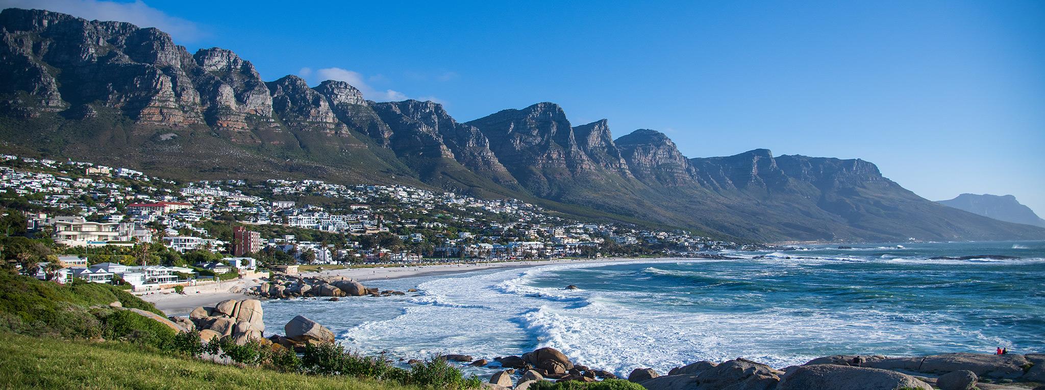 Cape Town coastline with Twelve Apostles mountains, beach town, and ocean waves.