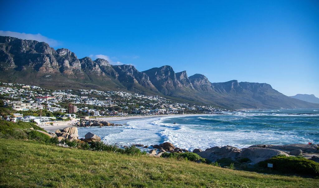 Cape Town coastline with Twelve Apostles mountains, beach town, and ocean waves.