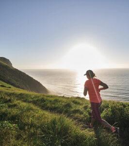 Umngazi guest running on a mountain trail above the ocean at sunset.