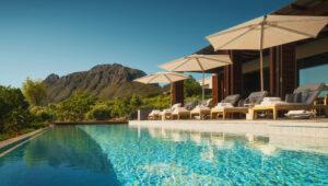 Infinity pool deck at Delaire Graff with loungers and sweeping mountain views.