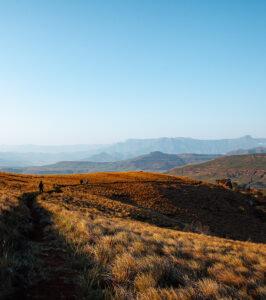 Hikers on a hiking trail towards the dramatic Drakensberg Mountain range, while on south africa trip.