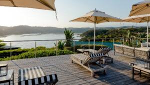 Wooden deck with lounge chairs and umbrellas overlooking Knysna water.