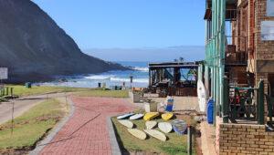 Colourful surf shack on George beach with surfboards lined up along the promenade.