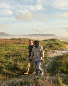 Guide and guest walk back from Noordhoek beach as part of a guided tour in South Africa.