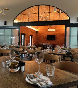 Elegant restaurant interior in Knysna at Hollow Country Estate, South Africa, with brick walls and wooden tables.