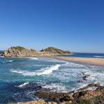South African beach with turquoise waters and rocky cliffs at Robberg Nature Reserve.