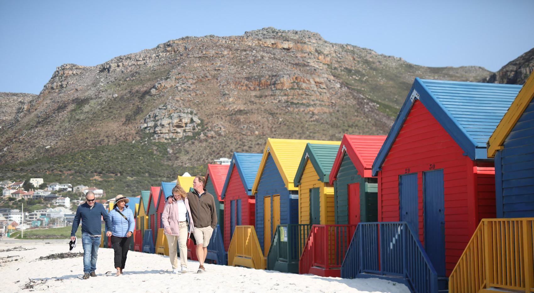 Colorful beach huts in Cape Town with people walking. Colorful beach huts in Cape Town with people walking.