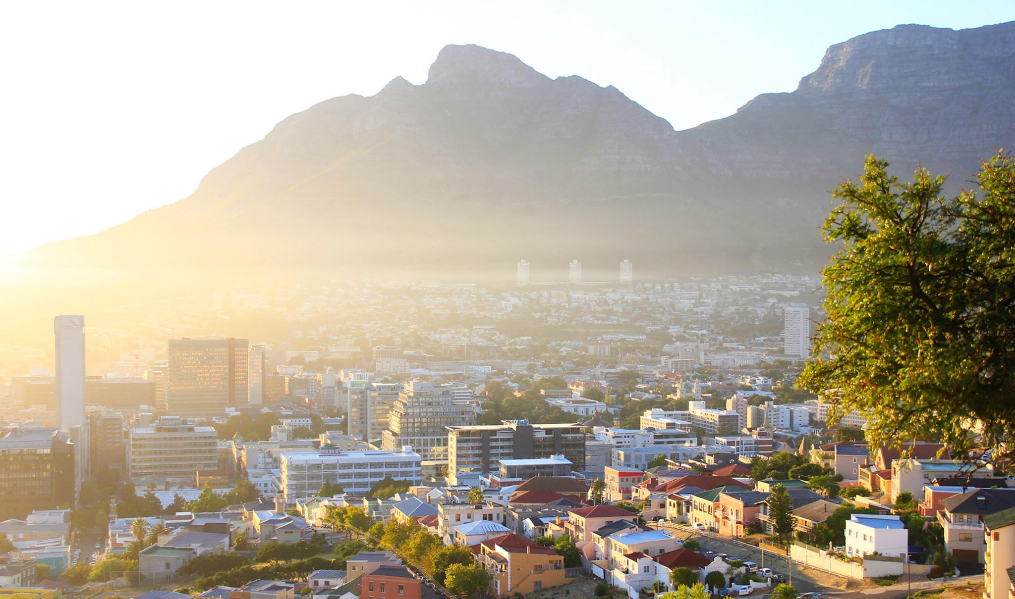 Cape Town cityscape at sunrise, with Table Mountain in the background.