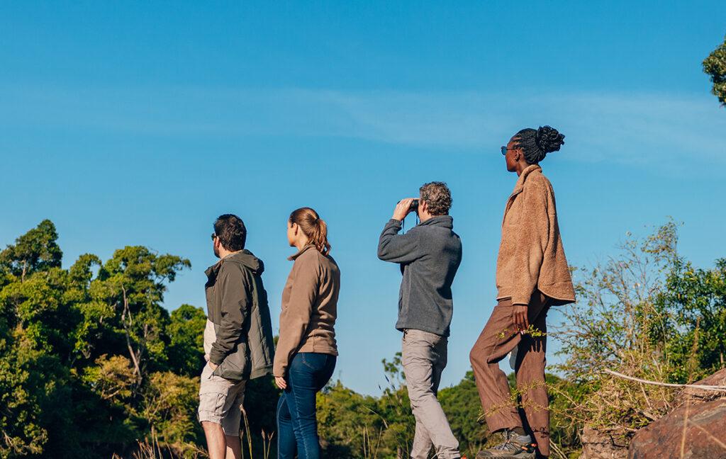 A group of people standing on a rock in single file.